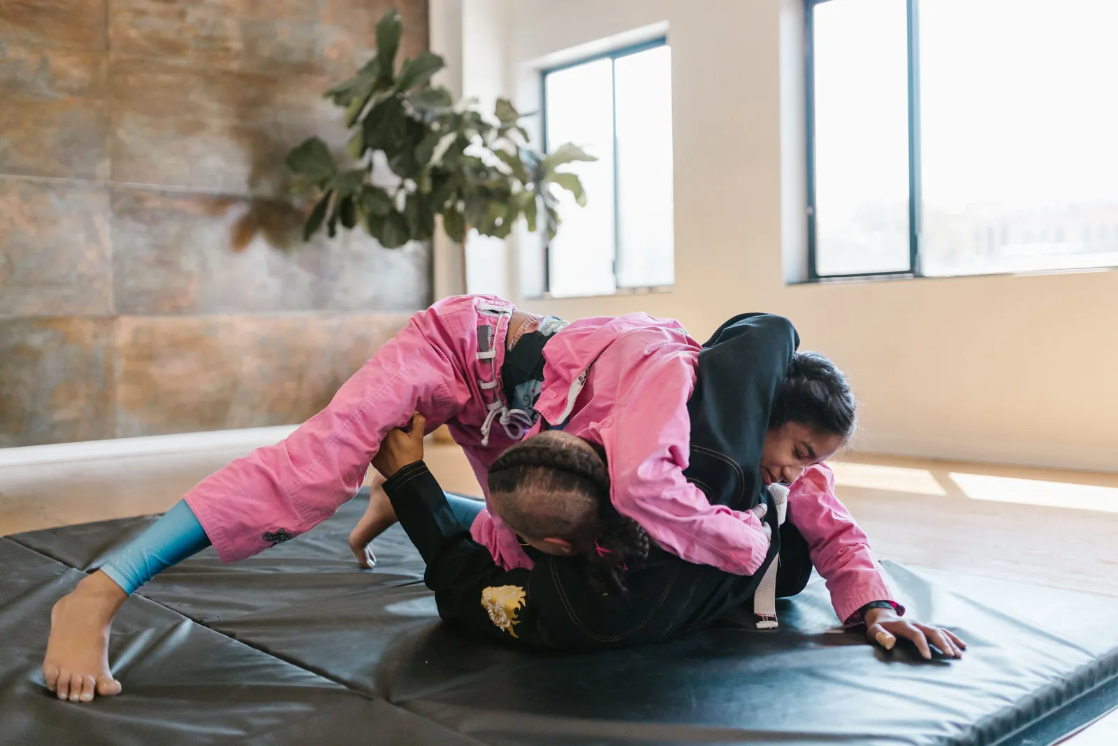 Nybörjarklass i brasiliansk jiu-jitsu — två utövare rullar lugnt på mattan